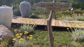 Un panneau indicateur en bois portant l’inscription « CASA FIORE DI MACHJA 0686374732 » et pointant vers la droite.
