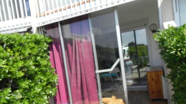 A patio with a blue table and chairs, a wooden door, and a glass sliding door. - pleasant studio for spa guests (Balaruc-Les-Bains)