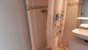 A bathroom with a shower curtain, a sink, and a toilet. - pleasant studio for spa guests (Balaruc-Les-Bains)