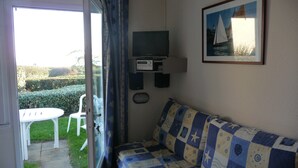 A small room with a sofa, a television, and a picture on the wall. - 2 roomed apartment for 4 to 5pers, ground garden, stunning sea views, à150m Beach (Arzon)