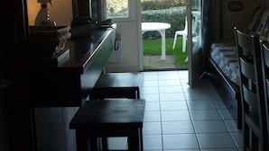 A kitchen with a dining area, a view of the garden, and a television. - 2 roomed apartment for 4 to 5pers, ground garden, stunning sea views, à150m Beach (Arzon)