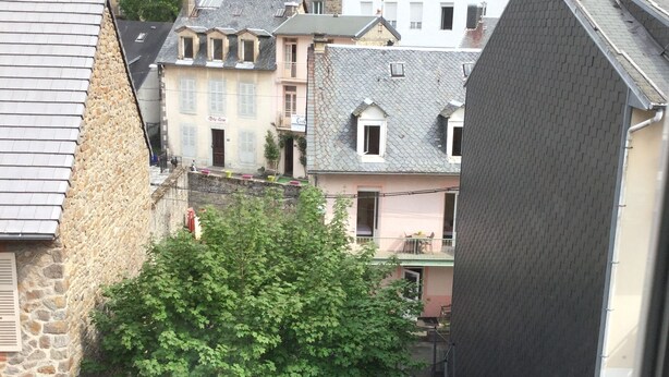 Une cour avec un arbre, des sièges extérieurs et des bâtiments environnants.