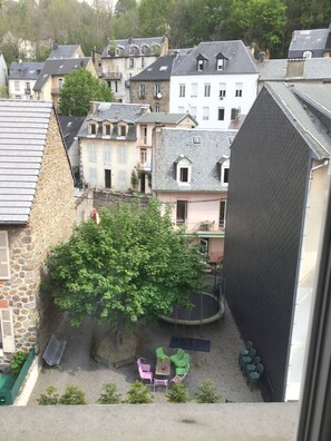 Une cour avec un arbre, des sièges extérieurs et des bâtiments environnants.