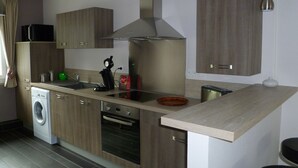 Une cuisine moderne dotée d’appareils électroménagers en acier inoxydable, de meubles en bois et d’un four encastré.