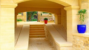 A stone archway leading to a courtyard with steps, potted plants, and a door in the background. - Charming house with private pool near Sarlat in beautiful grounds (Sarlat-La-Canéda)