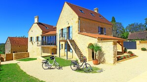 A stone house with a large balcony, a staircase, and a bicycle parked in front. - Charming house with private pool near Sarlat in beautiful grounds (Sarlat-La-Canéda)