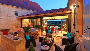 An outdoor patio area with wicker furniture, potted plants, and a dining setup. - Charming house with private pool near Sarlat in beautiful grounds (Sarlat-La-Canéda)