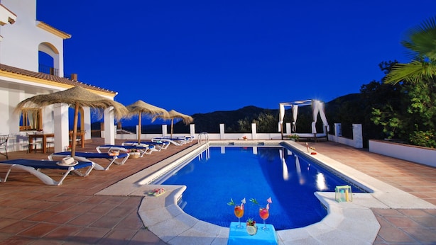A swimming pool with lounge chairs and umbrellas, surrounded by a building with white walls and a tiled roof. - Villa José 1, 12 Pers, Sea View ! Heated pool,  Wifi,A/C, petfriendly (Comares)