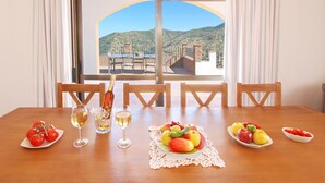 A dining table with a view of a mountainous landscape through a large window. - Villa José 1, 12 Pers, Sea View ! Heated pool,  Wifi,A/C, petfriendly (Comares)