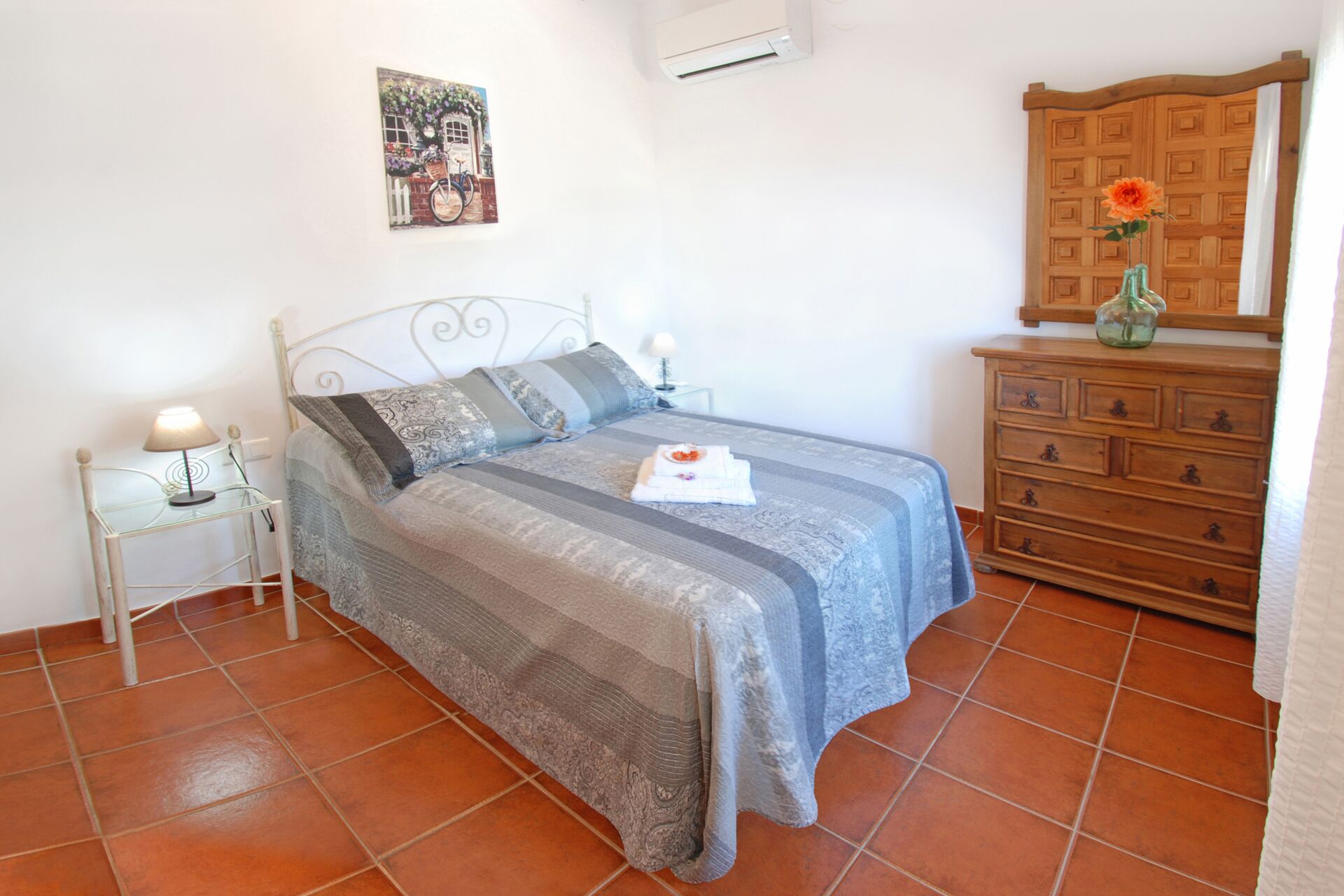 Ein Schlafzimmer mit einem Bett, Nachttischen, einer Kommode und einer Wand-Klimaanlage.
