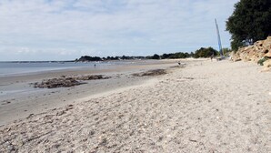 A beach with pebbles, a sandy shore, and a rocky outcrop.