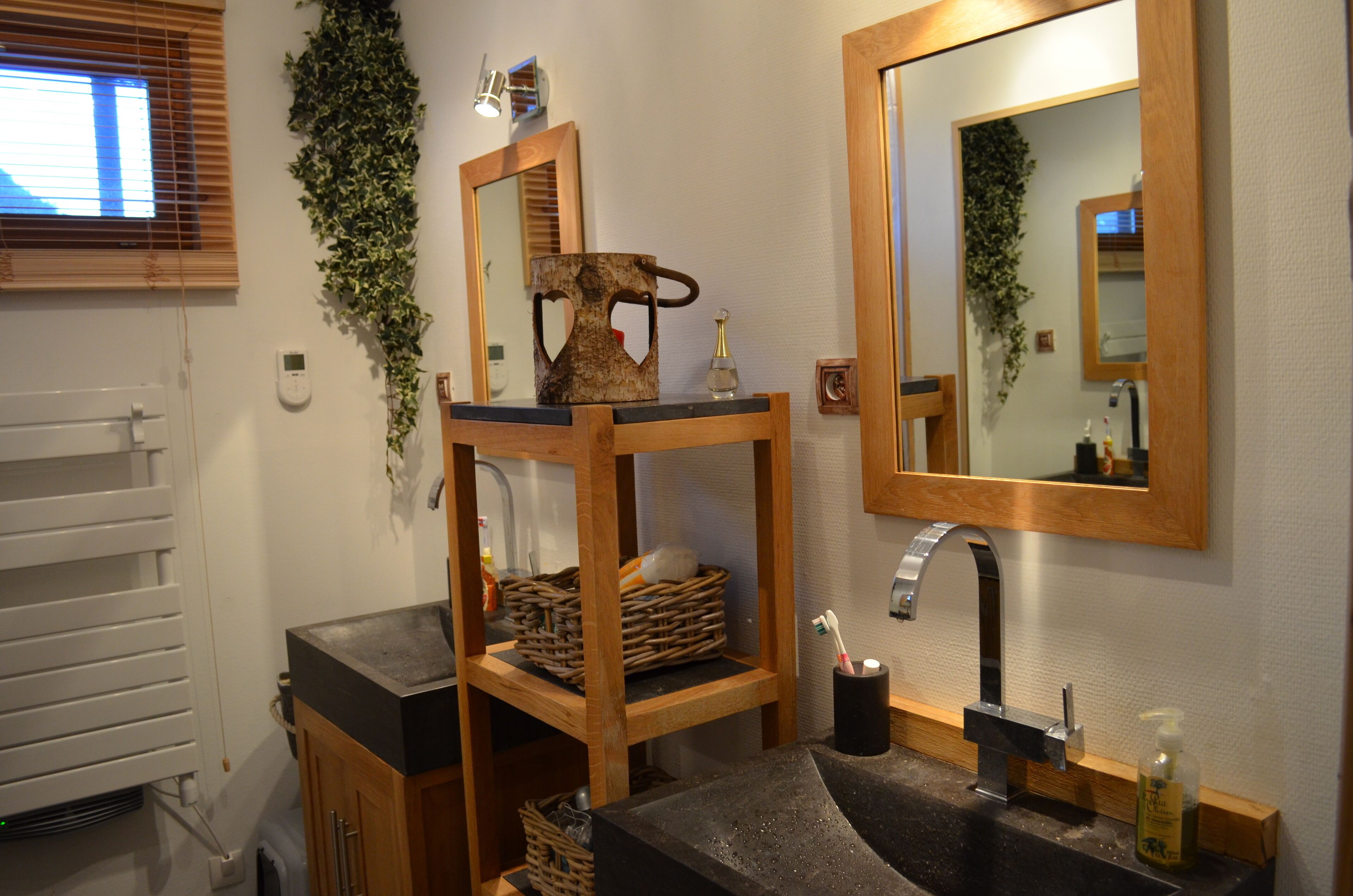 A bathroom with a wooden vanity, a mirror, a sink, and a radiator.