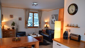 A cozy living room with a wooden dining table, a sofa with a Union Jack pillow, a coffee maker, and a toaster on the counter.