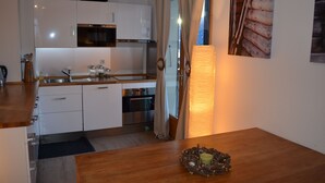 A modern kitchen with white cabinets, stainless steel appliances, and a wooden countertop.