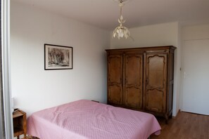 A bedroom with a bed, a wooden wardrobe, and a ceiling light fixture.