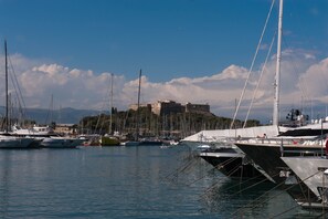 A marina with multiple boats docked, a castle in the background, and a clear sky.