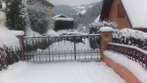 A snow-covered gate with a number plate, leading to a building with a sloped roof.