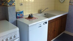 A compact kitchen with a white stove, a sink, and wooden cabinets.