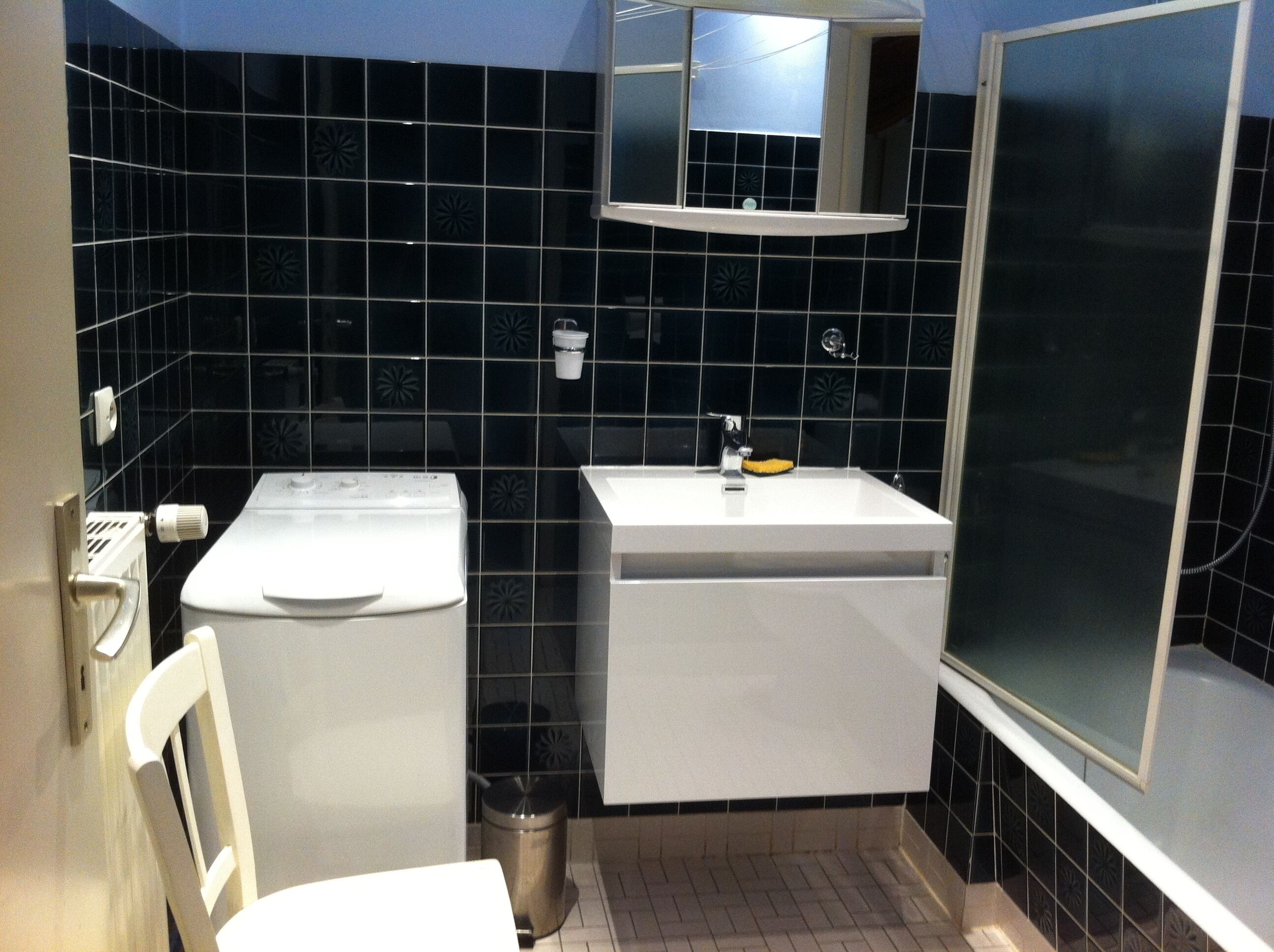 Un baño pequeño con un lavamanos blanco, un espejo encima y una zona de ducha.