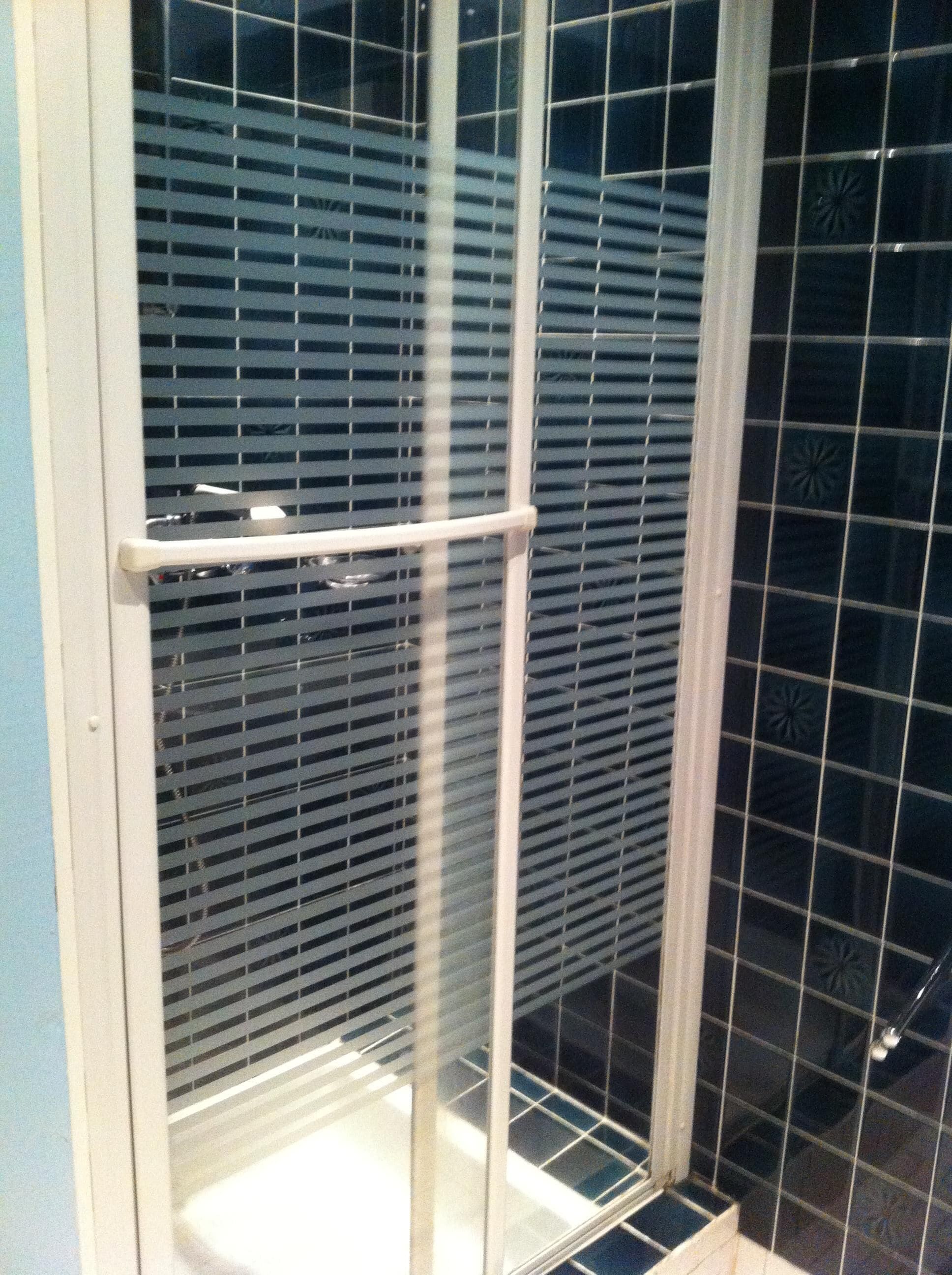 Une salle de bain avec une douche à parois de verre et un mur recouvert de carreaux.