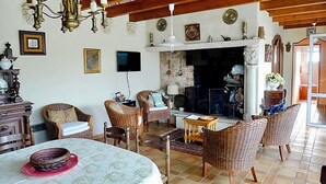 Ein gemütliches Wohnzimmer mit Korbmöbeln, einem Kamin und einem Fernseher.