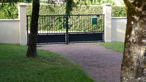 A gated entrance with a gravel path leading to a hedge. - nice country house close to ROYAN (Médis)