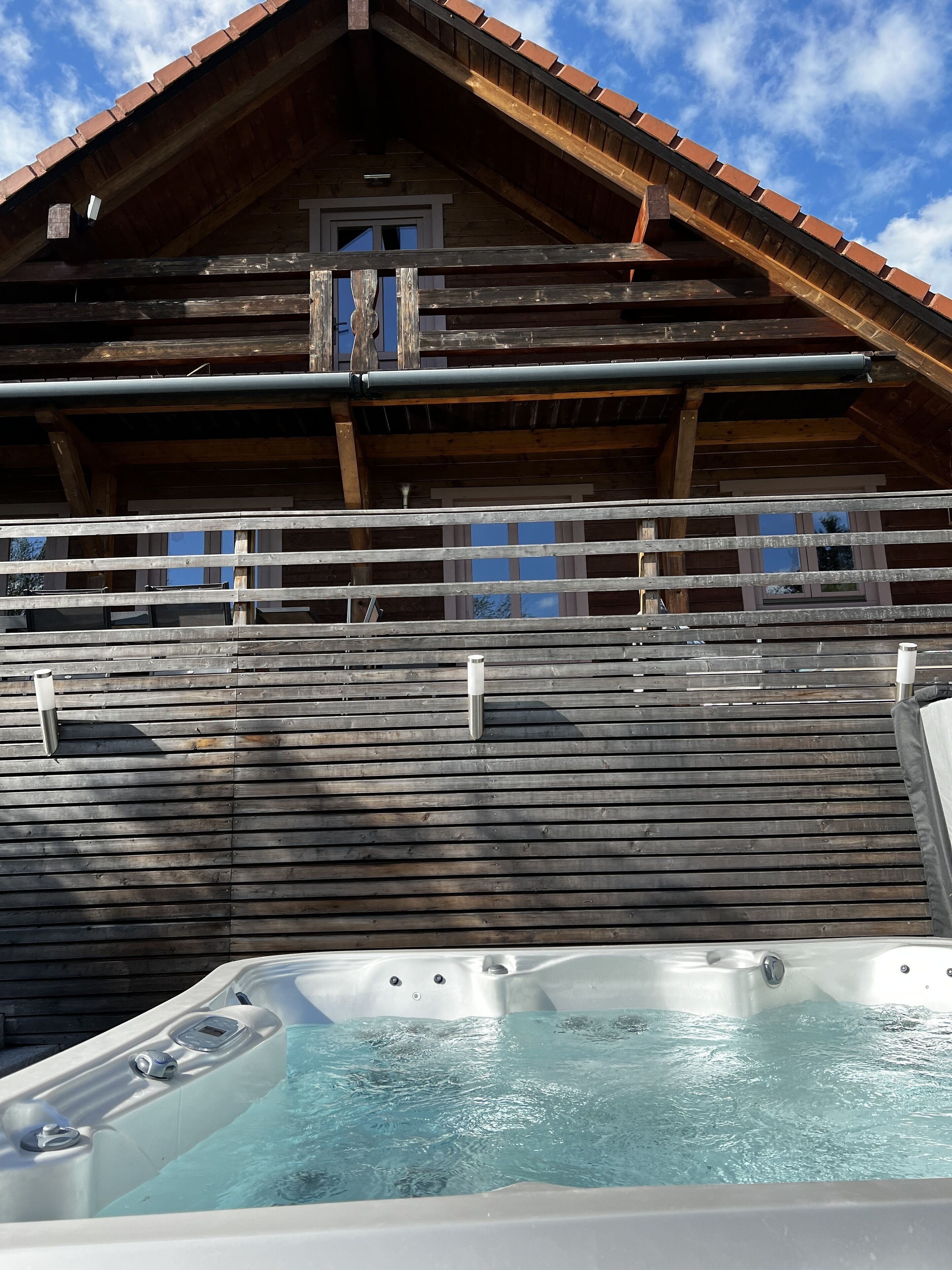 A wooden cabin with a hot tub in front.