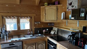 Eine Holzhüttenküche mit Geschirrspüler, Backofen und Kaffeemaschine.