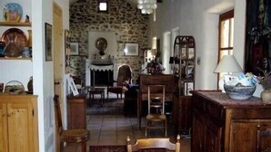 A cozy dining area with a stone wall, wooden furniture, and a fireplace. - Mas Cevenol with pool in Gagnieres (Gagnières)