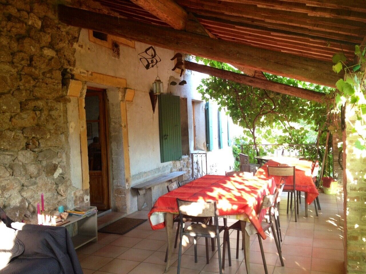 Zona de menjador a l'exterior amb parets de pedra, una pèrgola de fusta i taula ben a punt per a dues persones.
