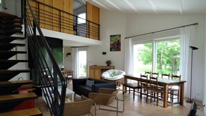 A spacious living area with a staircase, a dining table, and a sofa.
