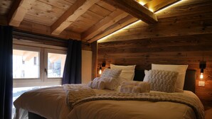 Un dormitorio de cabaña de madera con una cama, almohadas y una ventana.