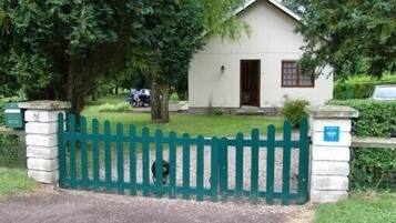 A small, white building with a green picket fence in front, surrounded by trees.