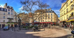 A cobblestone square with historic buildings, a fountain, and outdoor seating areas.