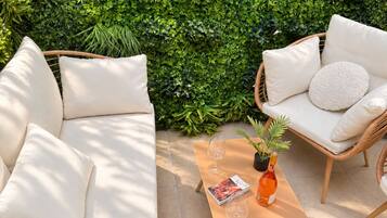 A patio with a sofa and chairs, a table, and a potted plant.