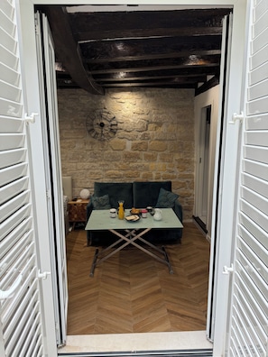 A cozy room with a stone wall, a clock, a table with a vase, and a sofa. - Private terrace, AC & quiet in the Latin Quarter (Paris)