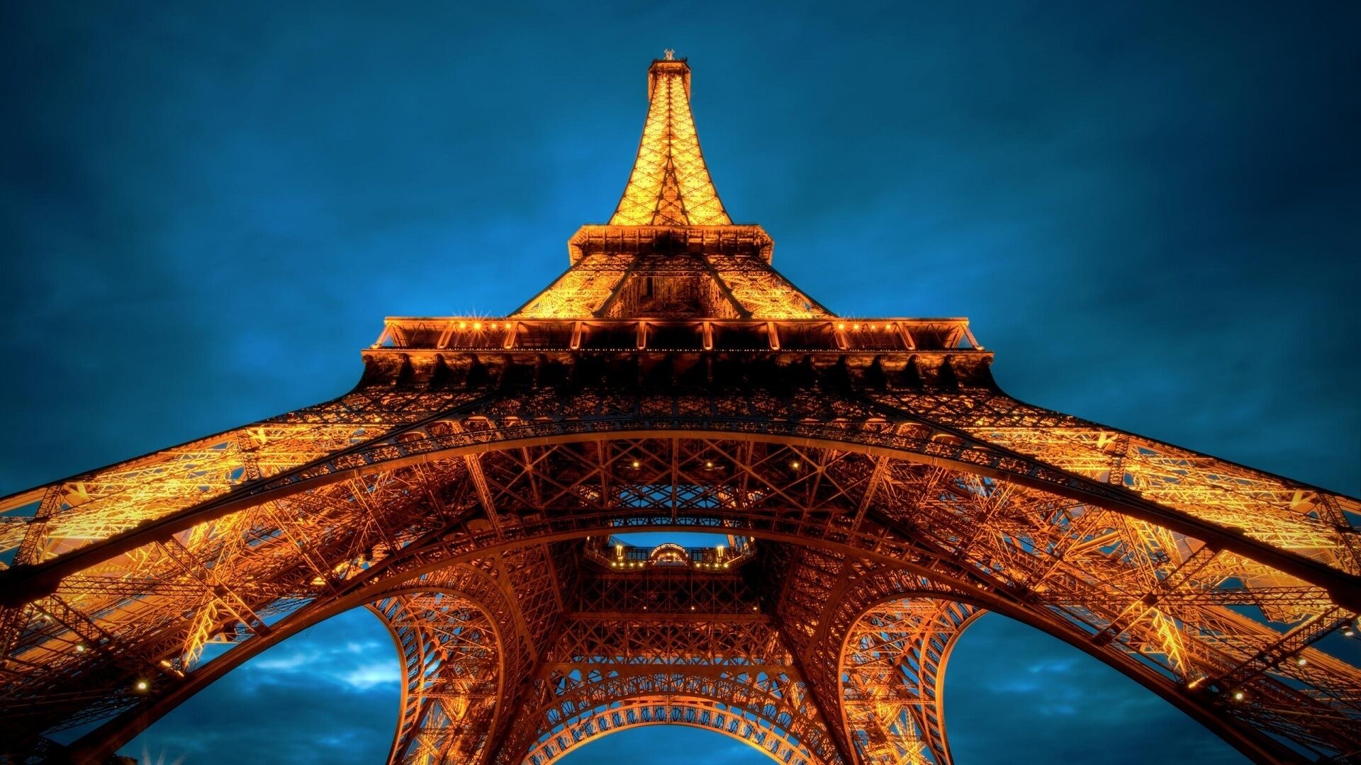 The Eiffel Tower's intricate iron lattice structure against a twilight sky.