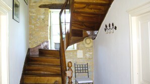 A wooden staircase with a stone wall, a hat on the wall, and a chair in the corner. - Beautiful view of the countryside house 8 pers pool Wifi near Sarlat (Salviac)