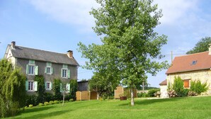 A residential area with a grassy lawn, a large tree, and two stone buildings with green shutters. - Beautiful view of the countryside house 8 pers pool Wifi near Sarlat (Salviac)