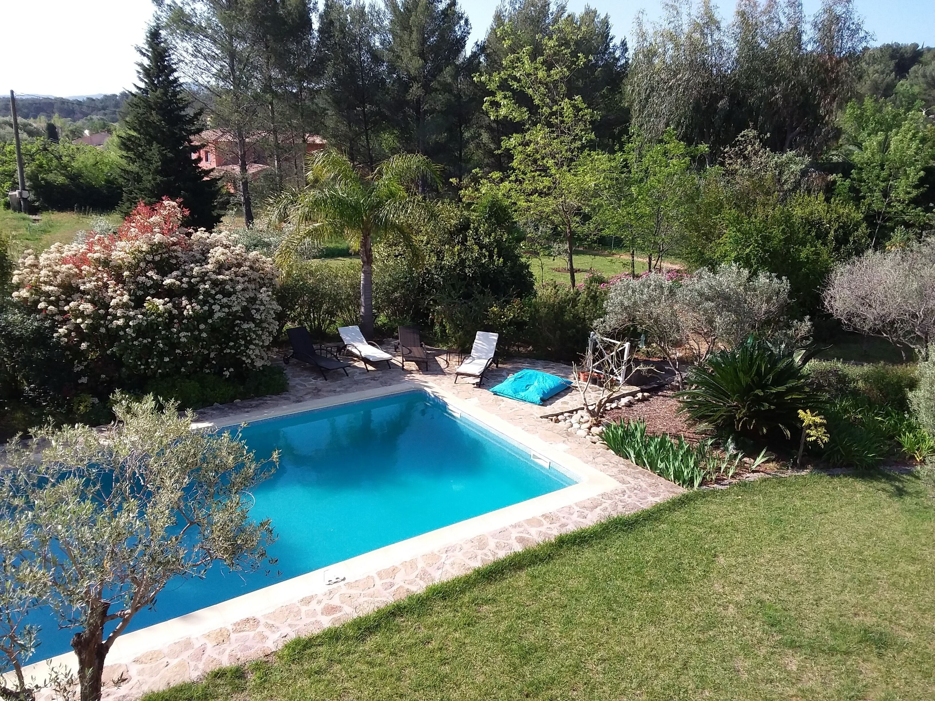 Una piscina con lettini da relax e un bordo in pietra.