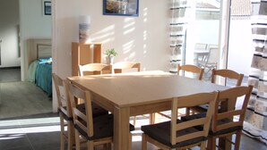 Ein Essbereich mit Holztisch und Stühlen, einer Topfpflanze und einem gerahmten Bild an der Wand.