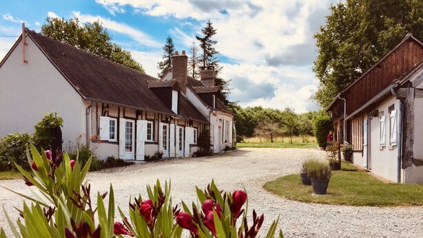 Ein traditionelles Gebäude im europäischen Stil mit Kiesweg und umgebender Bepflanzung.