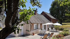 Ein Haus mit Kiesterrasse, Sitzgelegenheiten im Freien und einem Garten.
