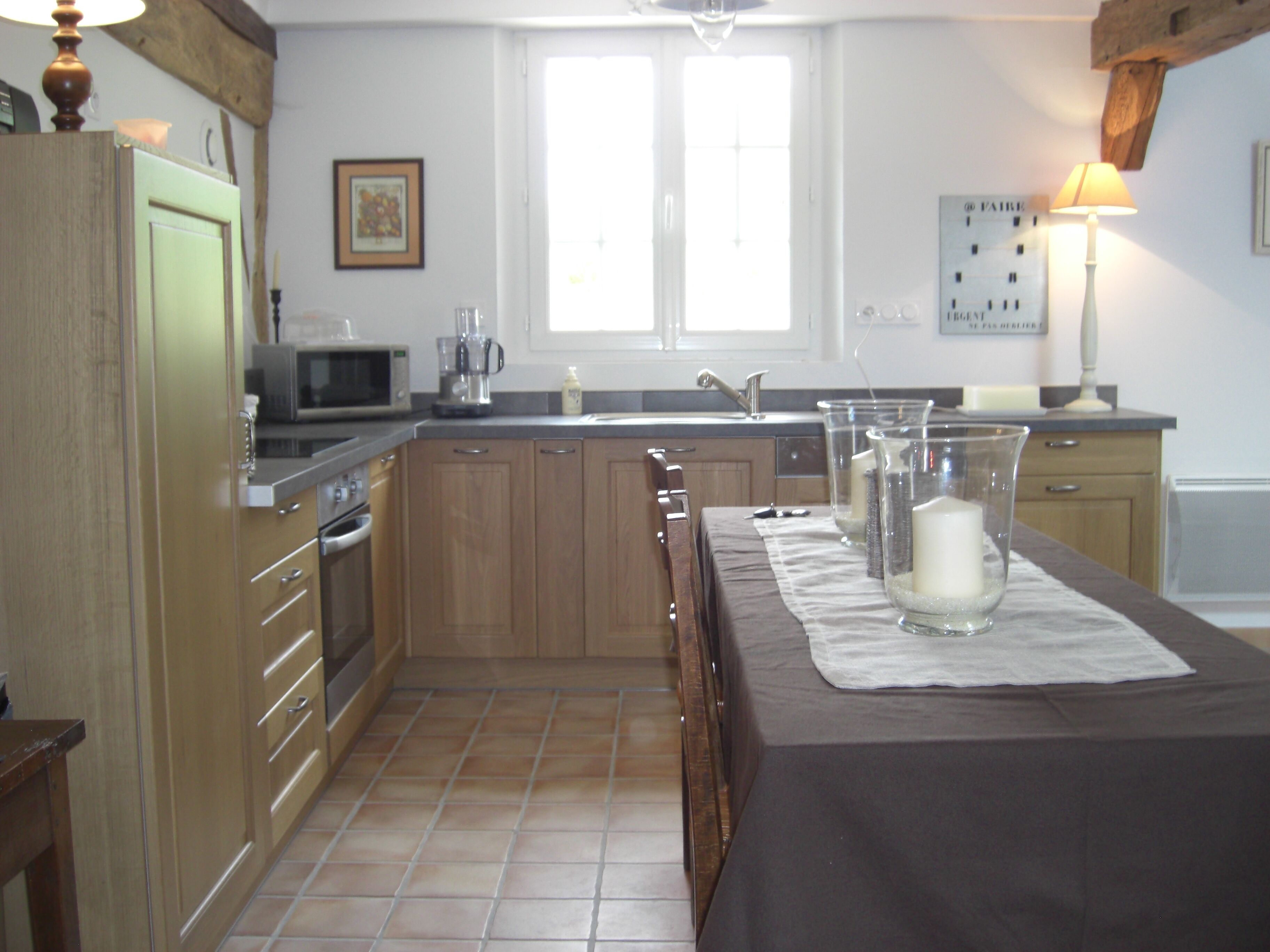 A kitchen with wooden cabinets, a microwave, a sink, and a dining table set with a placemat.