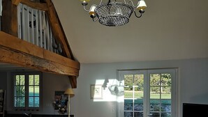 Ein geräumiges Wohnzimmer mit hoher Decke, einer Kandelaber, einem Sofa, einem Couchtisch und einem Fernseher.