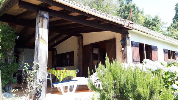 A rustic wooden building with a covered porch, stone walls, and a stone fireplace.
