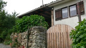 A rustic house with a stone wall, wooden gate, and a covered porch. - Quiet chalet, between sea and mountain (Isolaccio-Di-Fiumorbo)