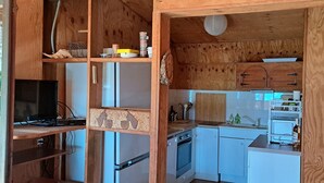 A compact kitchen with wooden cabinetry, a refrigerator, a stove, and a microwave. - Quiet chalet, between sea and mountain (Isolaccio-Di-Fiumorbo)