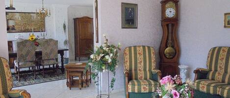 Una sala de estar tradicional con sillones estampados, una mesa de centro, un reloj grande y una araña.