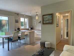 A modern kitchen with a dining area, a coffee machine, and a view of the outdoors. - DEAUVILLE, APPART AVEC JARDIN clos et équipé, 5 min DE LA MER, 5 Min des GOLF (Deauville)
